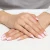 Delikatny złoty pierścionek o kształcie fali V, prezentowany na dłoni z paznokciami w stylu francuskiego manicure produktu AP230-333