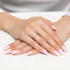 Złoty pleciony pierścionek skręcana obrączka bez kamieni szlachetnych, prezentowany na dłoni z paznokciami w stylu francuskiego manicure produktu AP229-333