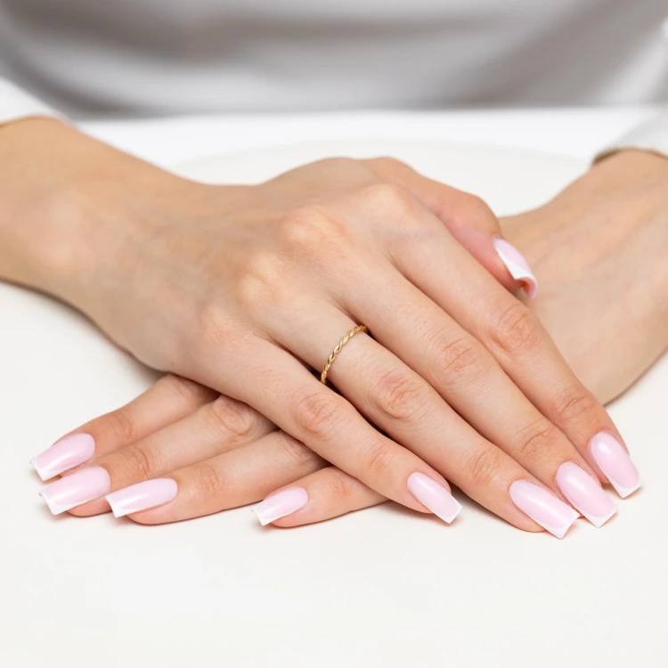 Złoty pleciony pierścionek skręcana obrączka bez kamieni szlachetnych, prezentowany na dłoni z paznokciami w stylu francuskiego manicure produktu AP229-333