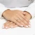 Elegancki, złoty pierścionek z kwadratowym diamentem laboratoryjnym Princessa otoczonym mniejszymi białymi diamentami, prezentowany na dłoni z jasnoróżowym manicure produktu W0590.Z3.LDW.01
