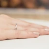 Elegancki pierścionek zaręczynowy z różowego złota z maleńkim brylantem, prezentowany na dłoni z paznokciami w kolorze nude, produktu W0222.R3.DIW.01