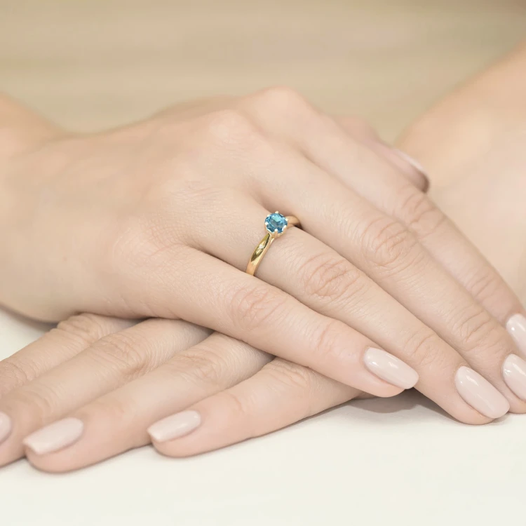 Złoty pierścionek zaręczynowy z topazem Swiss z kolekcji Kultowa, prezentowany na dłoni produktu W0074.Z3.TOB.01