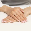 Złoty delikatny pierścionek w kształcie litery V z pojedynczą cyrkonią, prezentowany na dłoni z wykonanym manicure, produktu AP176-333-B