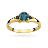 Elegancki pierścionek z żółtego złota z centralnie osadzonym okrągłym topazem London Blue, flanked by two black diamonds, prezentowany na białym tle produktu W0076.Z3.TOL.02