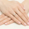 Elegancki pierścionek z żółtego złota z centralnie osadzonym, okrągłym diamentem laboratoryjnym prezentowany jest na kobiecej dłoni z różowym manicure produktu W0553.Z3.LDW.03