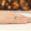 Złoty pierścionek z błyszczącym diamentem laboratoryjnym o okrągłym szlifie, prezentowany na dłoni z subtelnym różowym manicure produktu W0542.Z3.LDW.04