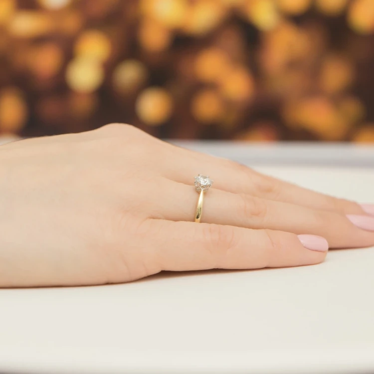Delikatny pierścionek z żółtego złota z centralnym diamentem laboratoryjnym otoczonym mniejszymi diamentami laboratoryjnymi, prezentowany na dłoni produktu W0539.Z3.LDW.02