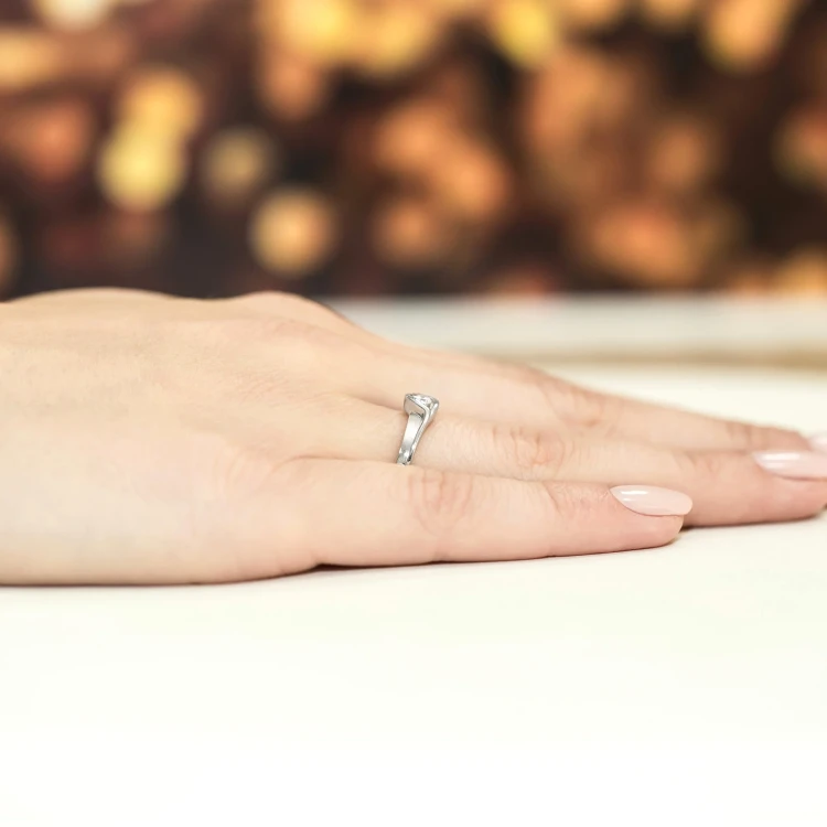 Elegancki pierścionek zaręczynowy z białego złota z brylantem, prezentowany na dłoni z subtelnym manicure produktu W0178.B3.DIW.02 marko