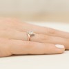 Elegancki pierścionek z różowego złota ozdobiony centralnym białym szafirem otoczonym brylantami, prezentowany na kobiecej dłoni produktu P038-R585-BS0.60