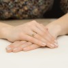 Dwa połączone pierścionki w kształcie litery V, jeden w kolorze żółtego złota, drugi w kolorze różowego złota, ozdobione drobnymi brylantami, prezentowane na dłoni produktu W0602.R3.DIW.01