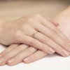 Delikatny pierścionek z żółtego złota z trzema drobnymi brylantami, prezentowany na dłoni produktu P016-B585-B0.02