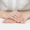 Złoty pierścionek z białymi i czarnymi cyrkoniami z kolekcji Kleur, prezentowany na dłoni z jasnoróżowym manicure, na białym tle produktu EP039-333