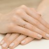 Elegancki pierścionek z różowego złota w kształcie litery V, ozdobiony drobnymi brylantami, prezentowany na dłoniach kobiety z delikatnym manicure, produktu W0602.R3.DIW.01